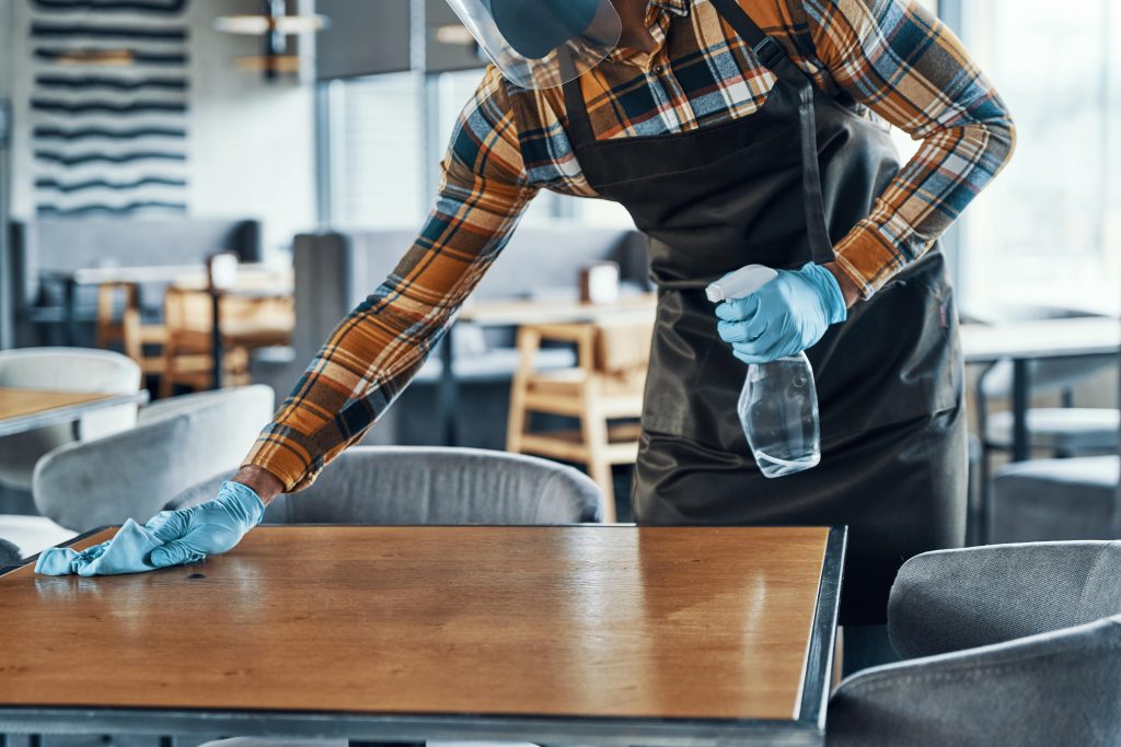 Restaurant and Bar Cleaning - man in cleaning gear wiping restaurant table