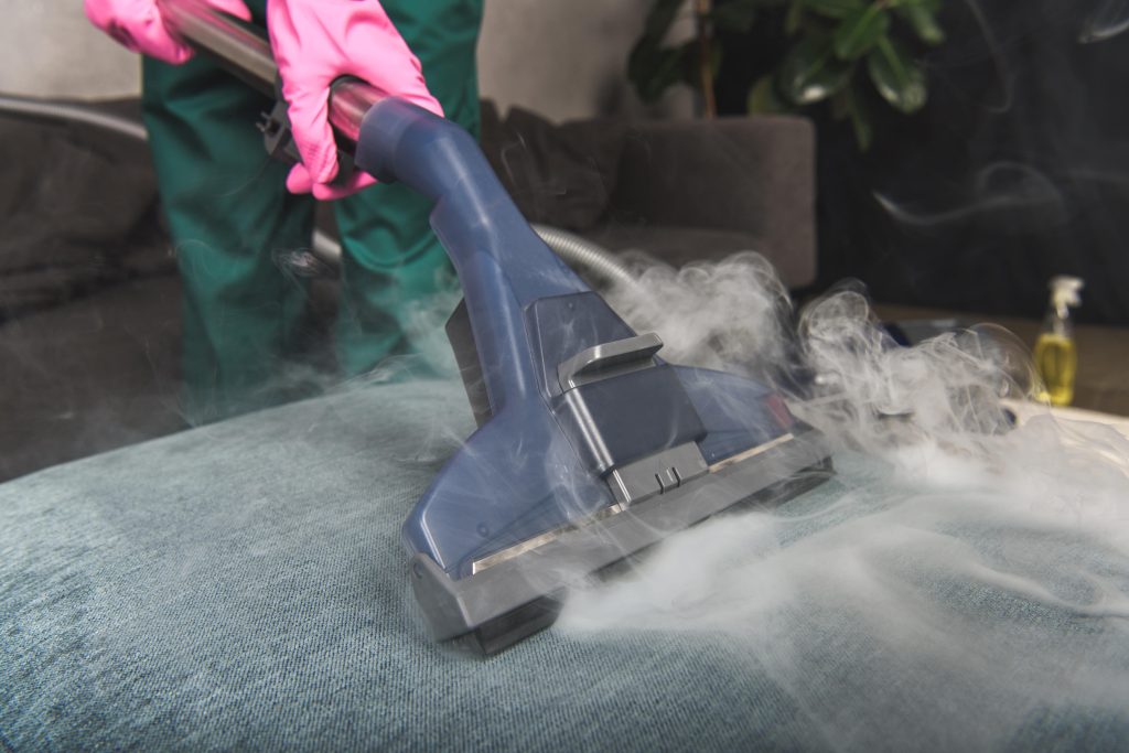 Upholstery Cleaning Services - person using steam cleaner to clean upholstery